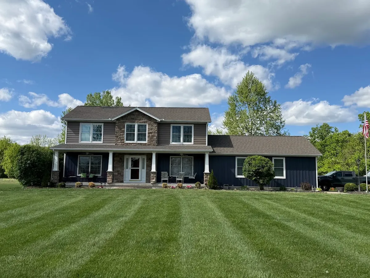 Dark board-and-batten siding paired with stone accents on a two-story home in Loveland, Ohio by Abrams Restoration