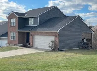 Completed gray vinyl siding replacement with brick accents and white trim on a two-story home in New Richmond, Ohio