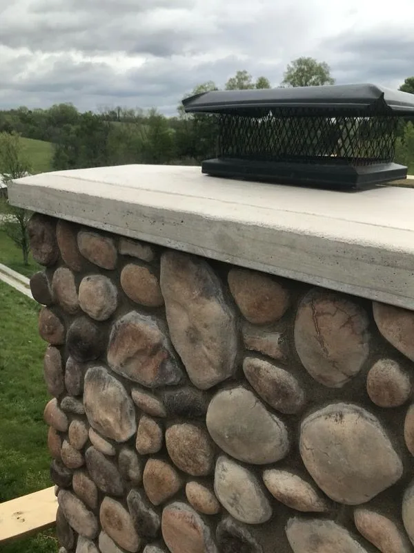 River rock chimney with newly poured concrete crown and stainless steel cap in Cincinnati, Ohio