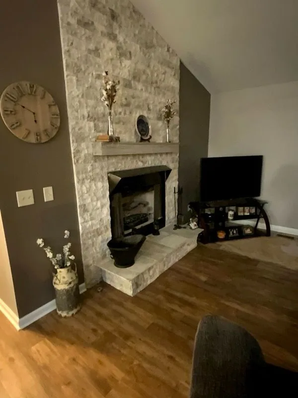 Floor-to-ceiling stacked stone fireplace surround with wood mantel in a remodeled living room in Loveland, Ohio