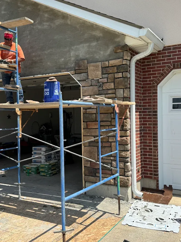 Stone veneer being installed on the front of a brick home with scaffolding in Cincinnati, Ohio