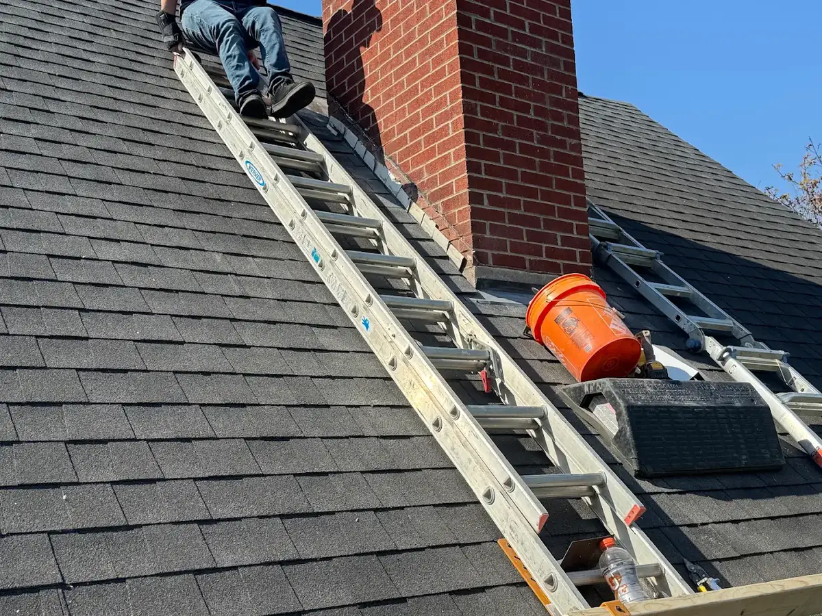 Roofer repairing shingles and chimney flashing on a residential roof in Clermont County, Ohio
