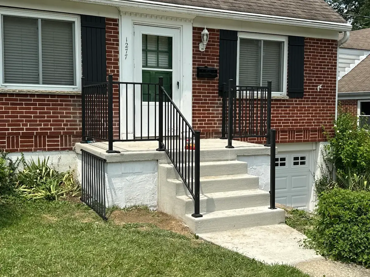 Rebuilt concrete front porch with black aluminum railings on a brick home in Amelia, Ohio by Abrams Restoration